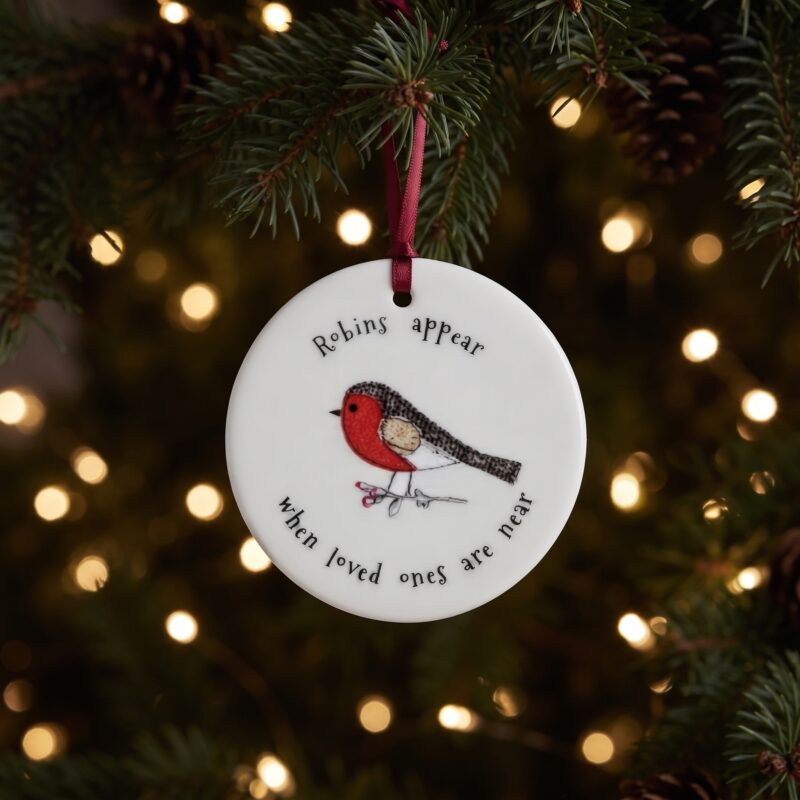 Robins Appear When Loved Ones Are Near ceramic decoration hanging in front of warm fairy lights